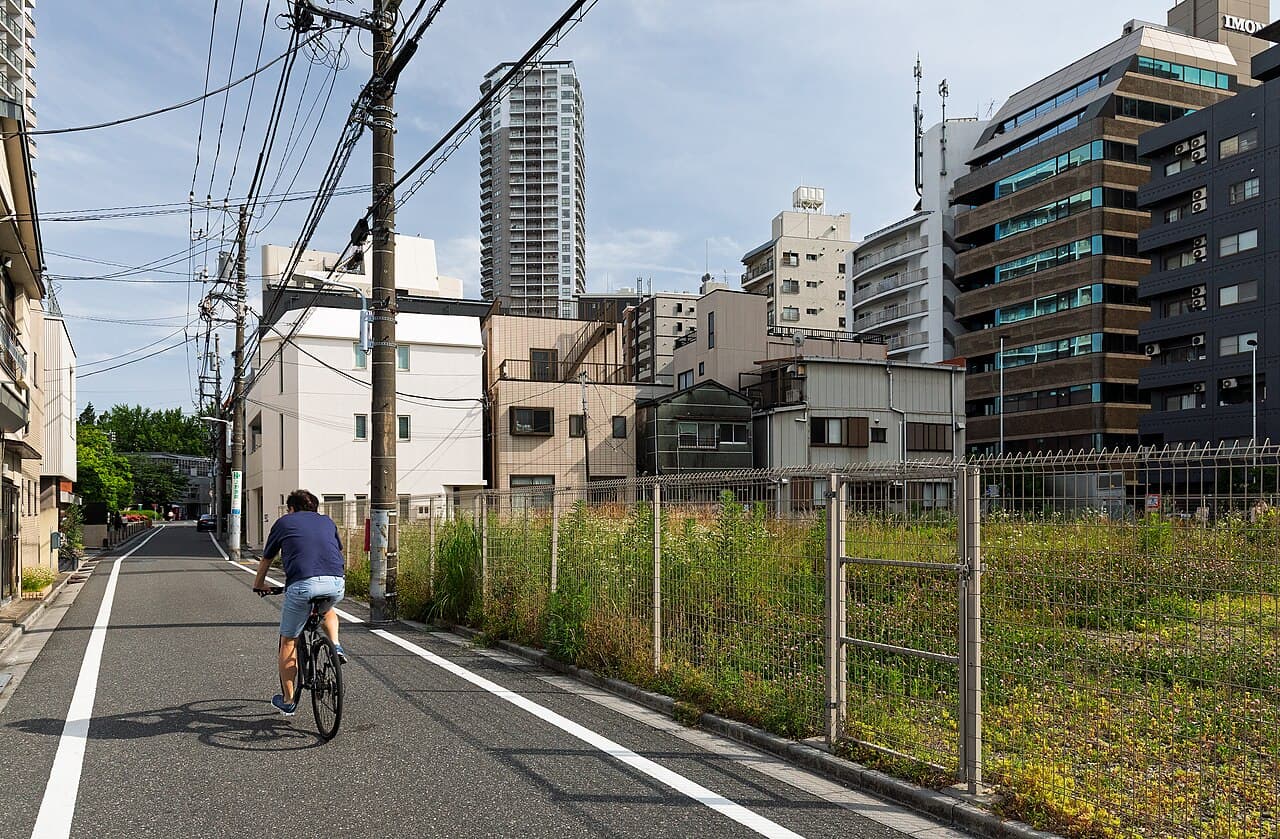 A mixed residential and commercial street in Ikenohata, Taitō, Tokyo, with an empty fenced lot awaiting redevelopment — illustrative of the ordinary neighbourhoods and small sales this piece discusses, not a specific listing or agency